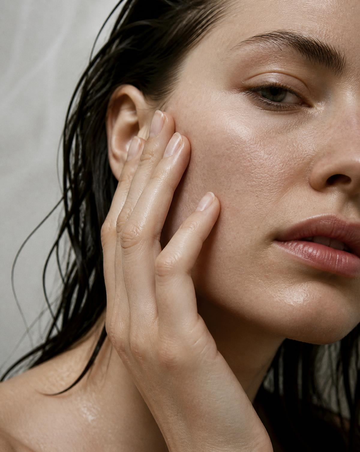 Femme touchant sa joue après la douche, peau qui tiraille.